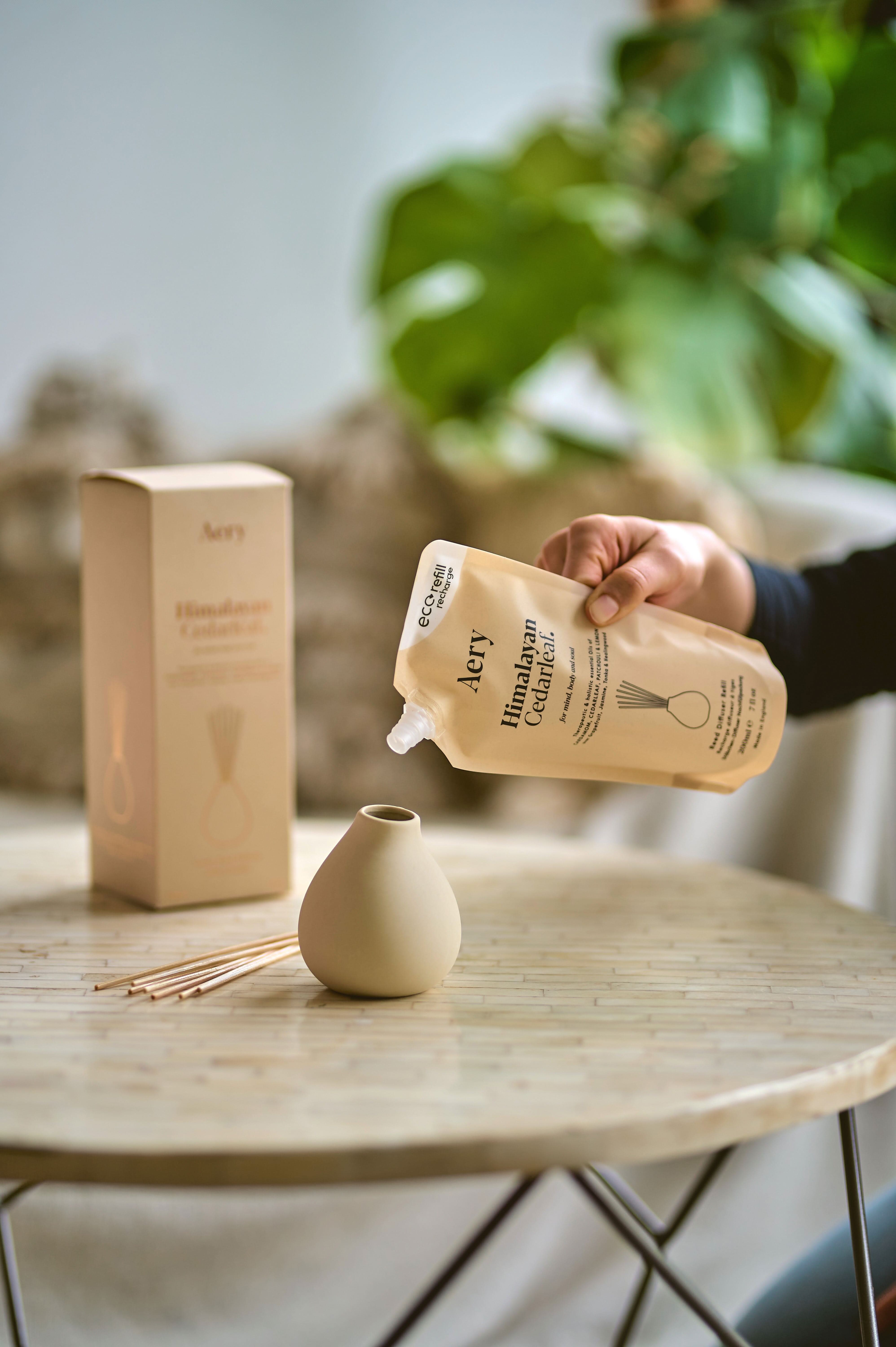 Hand pouring refill pouch into diffuser vase