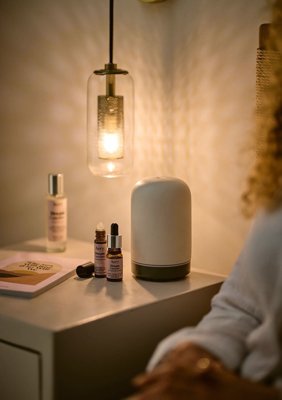 Lilac Dream Catcher pulse point oil displayed next to Dream Catcher fragrance oil and pillow mist on bedside table