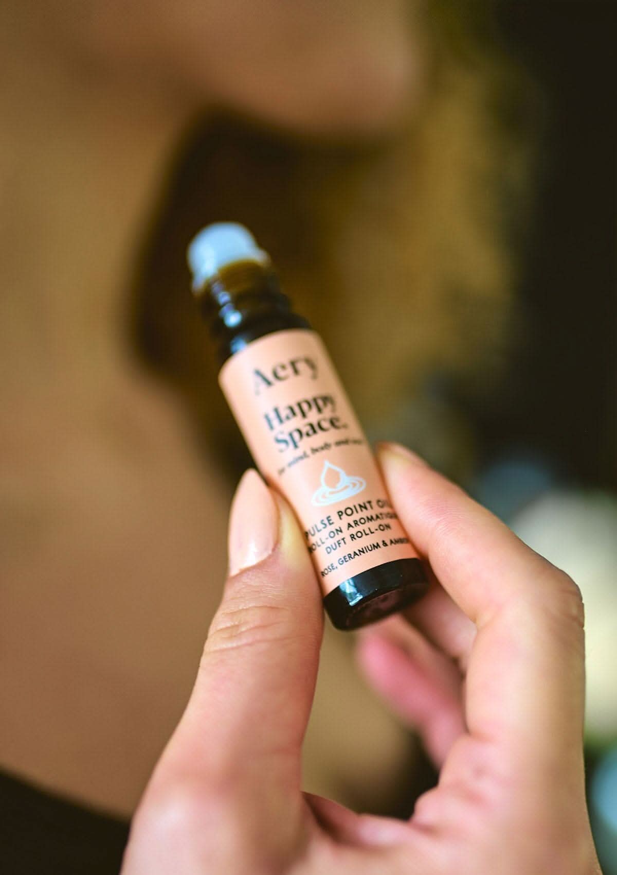 Pink Happy Space pulse point oil by aery held in hand