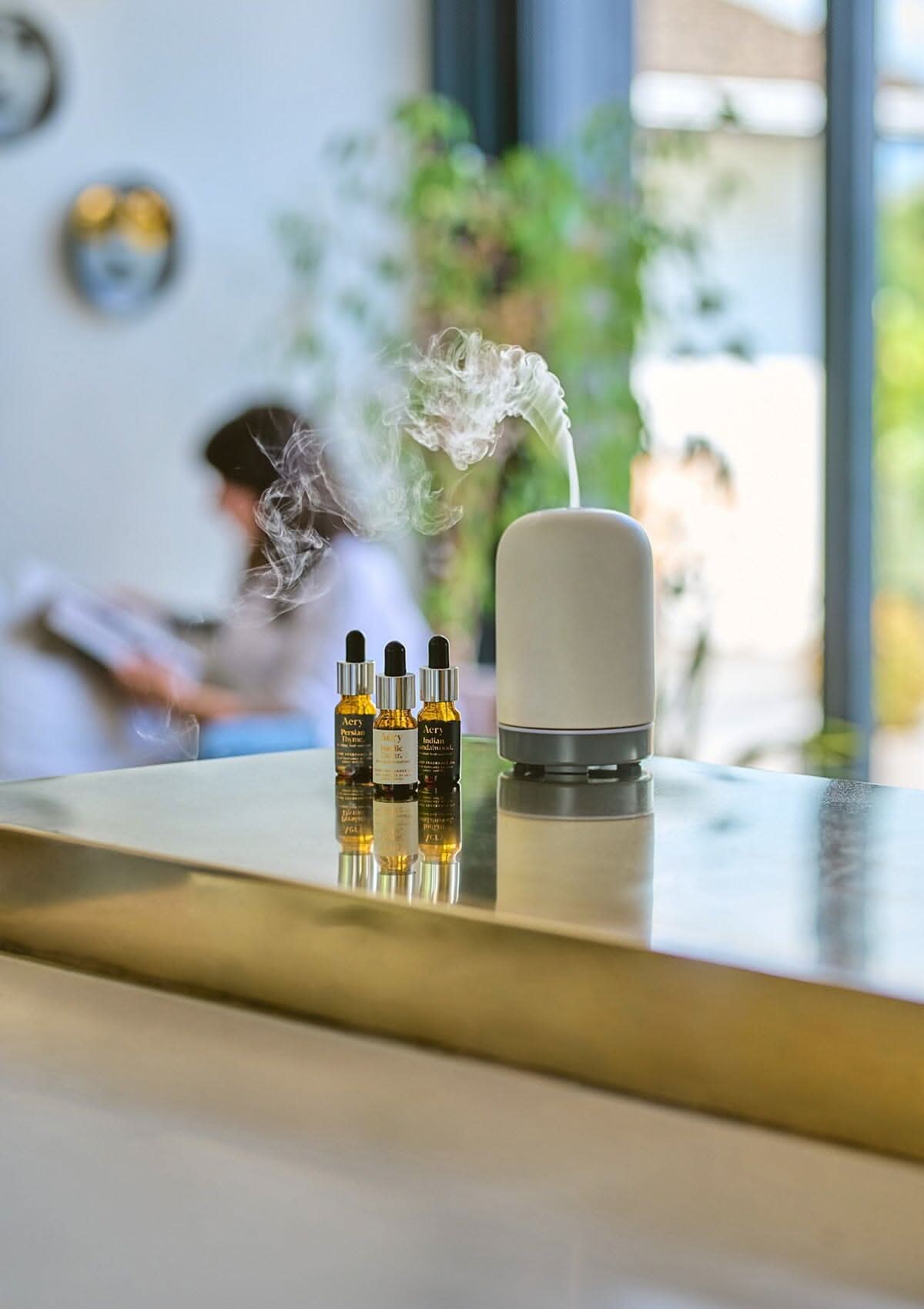 Black Indian Sandalwood fragrance oil by Aery displayed next to Persian Thyme and Nordic Cedarleaf fragrance oils and electric diffuser placed on gold kitchen work top