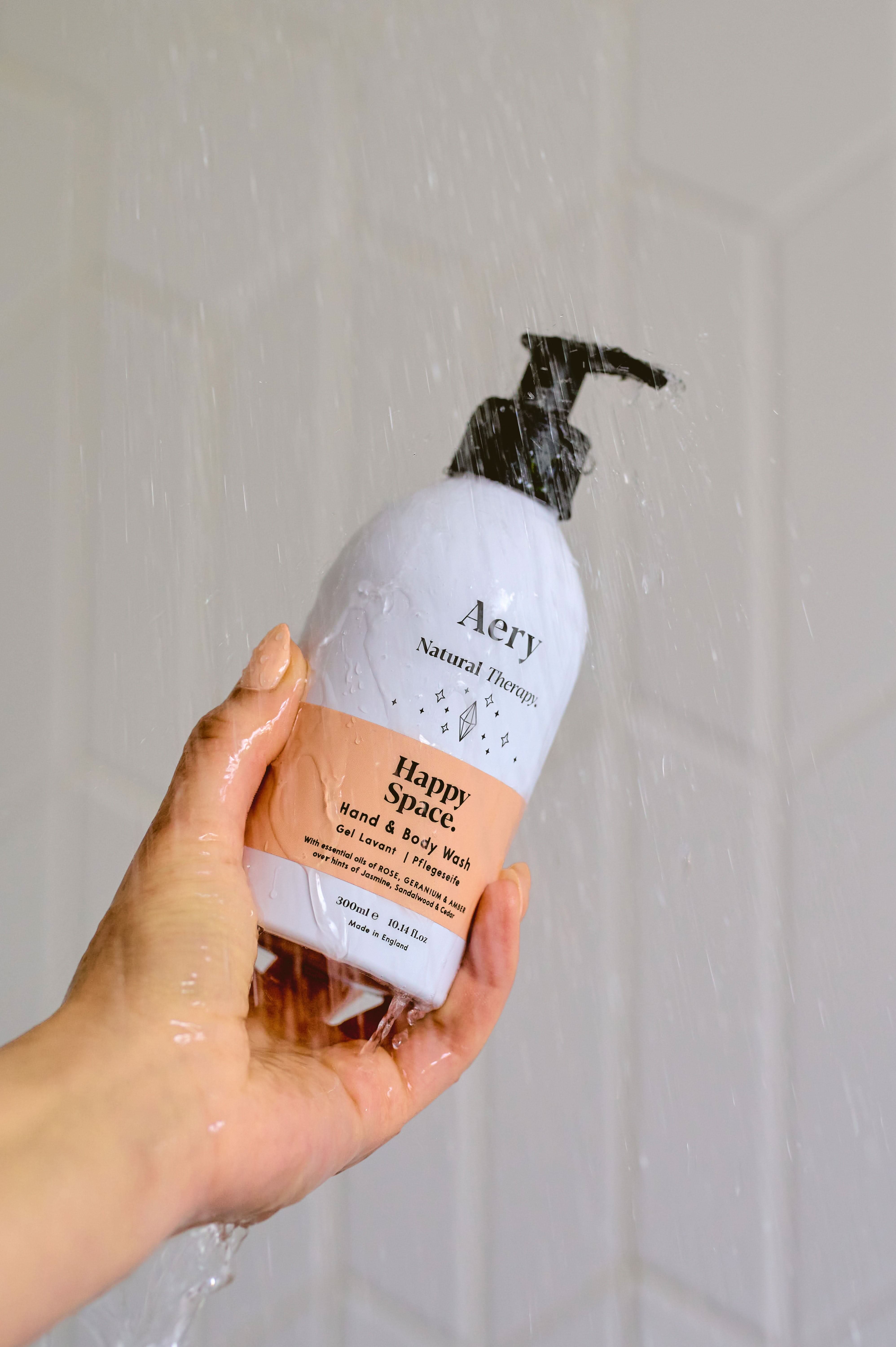 Pink Happy Space hand and body wash by Aery displayed in hand in shower