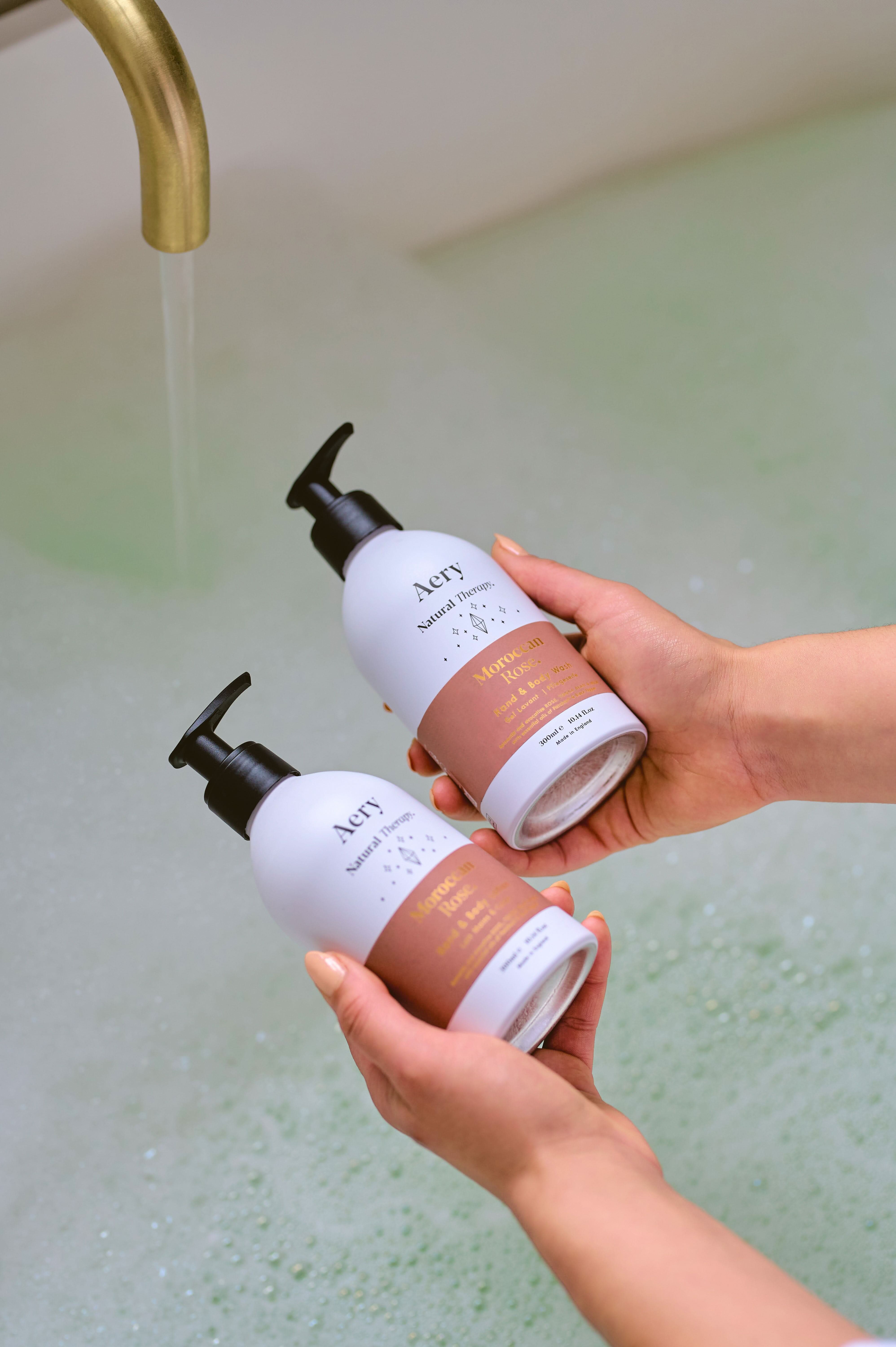Aubergine Moroccan Rose hand and body wash and lotion duo by Aery displayed in hands over bubble