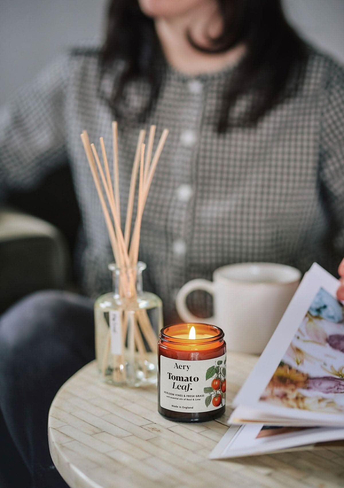Tomato Leaf jar candle by Aery displayed on circle table next to diffuser