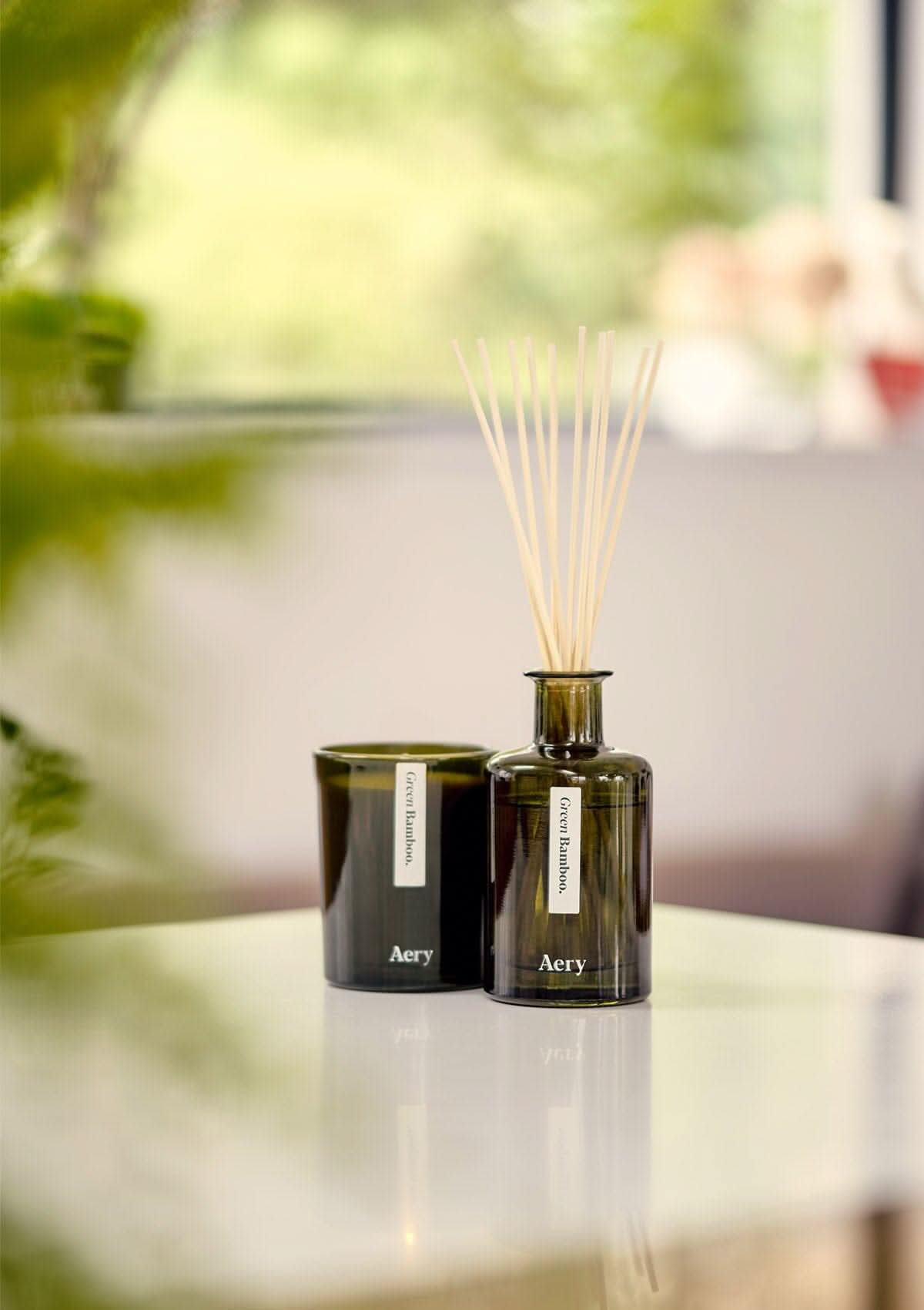 Green Bamboo diffuser by Aery displayed next to green bamboo candle placed on kitchen workspace