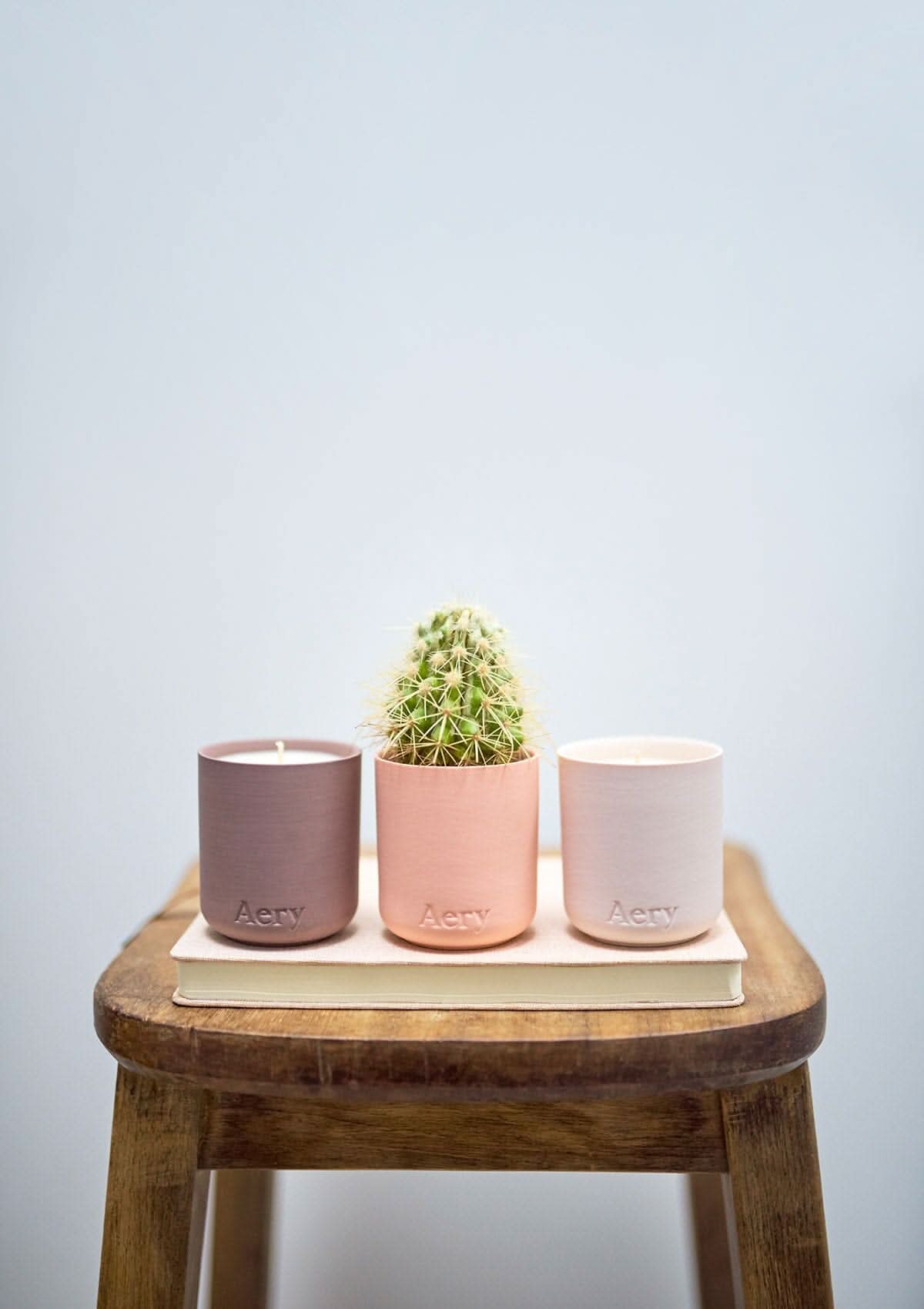 Pink Wanderlust set of three candles by Aery placed in a row on wooded stool