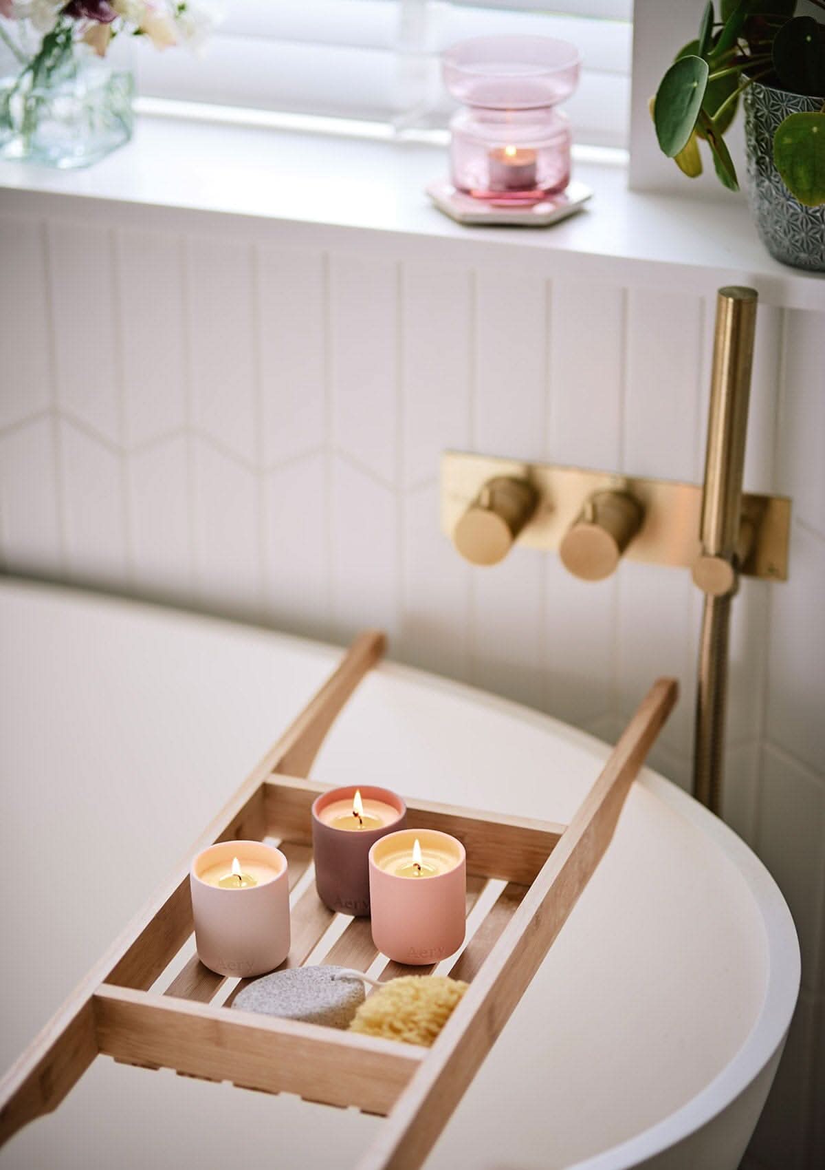 Pink Wanderlust set of three candles by Aery placed on wooden bath tray in bathroom