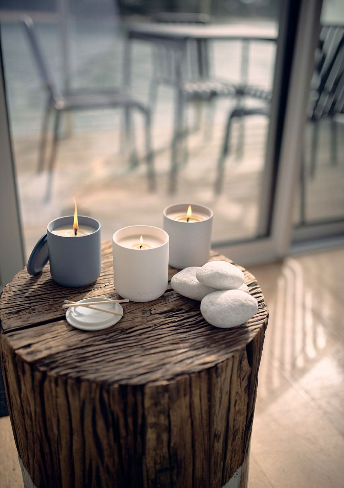 Wonderland set of three candles by Aery displayed on wooden stall with grey pebbles