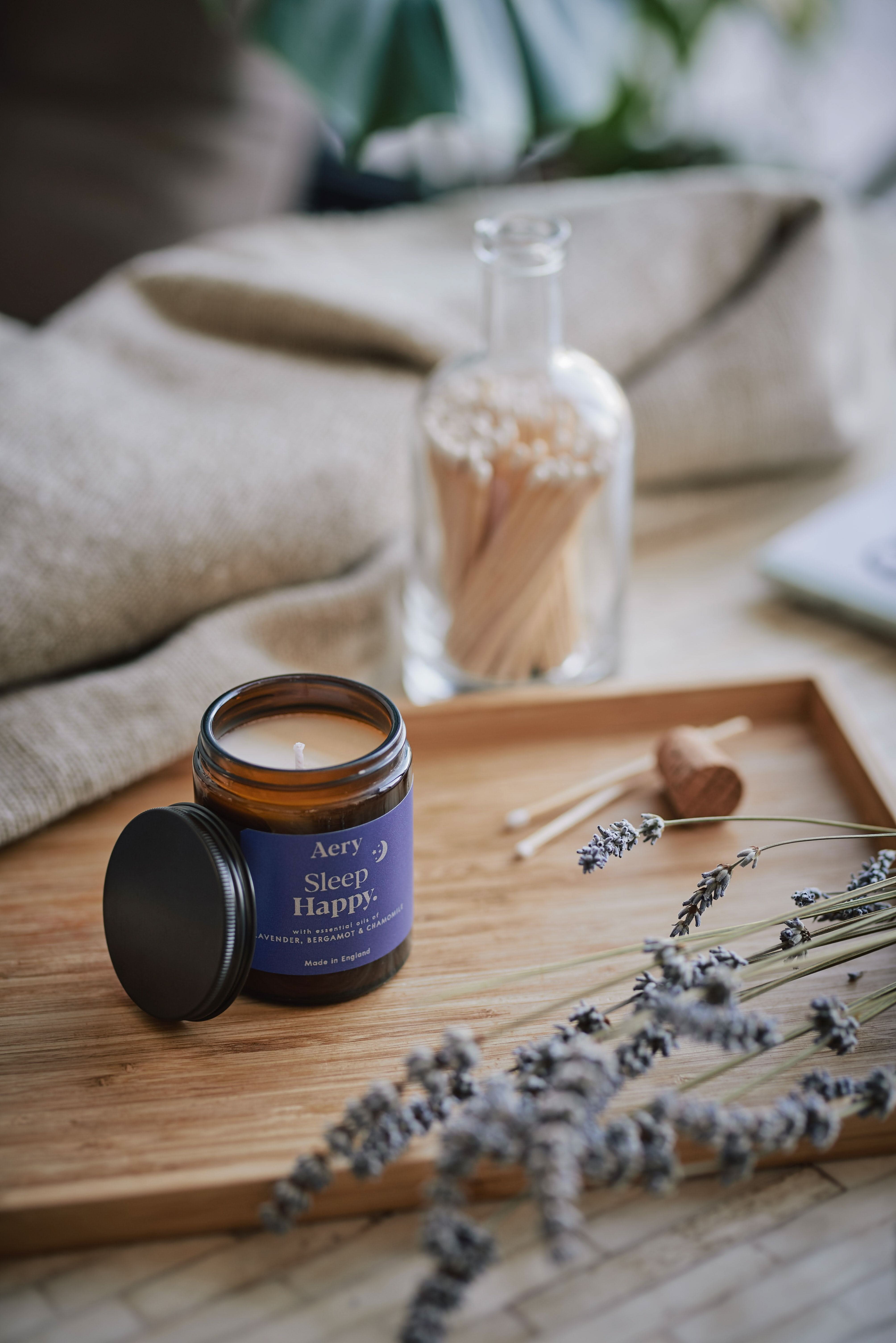 Blue Sleep Happy jar candle by Aery displayed on wooden tray with lavender and match sticks