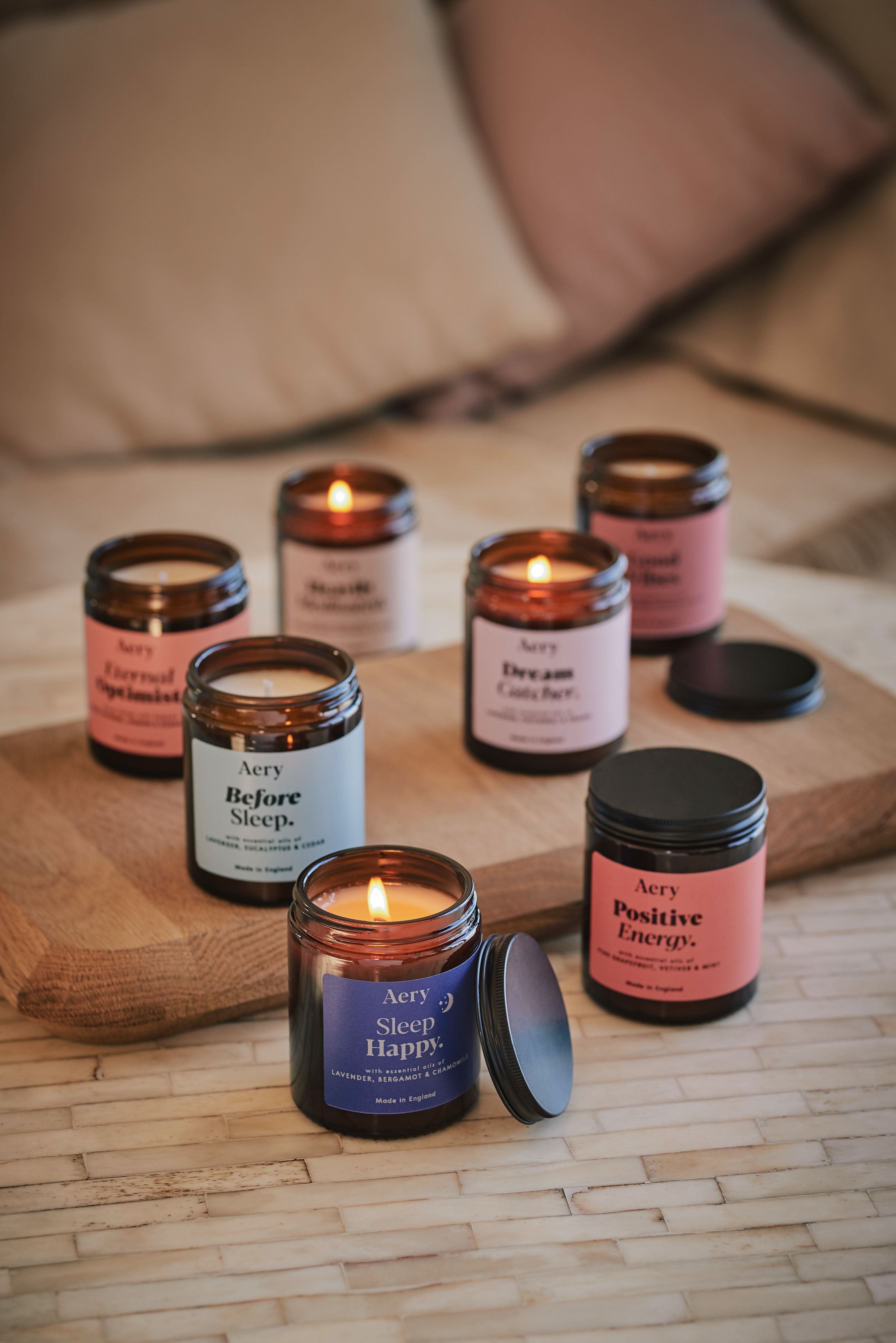 Collection of Aromatherapy jar candles by Aery displayed on wooden tray and cream table