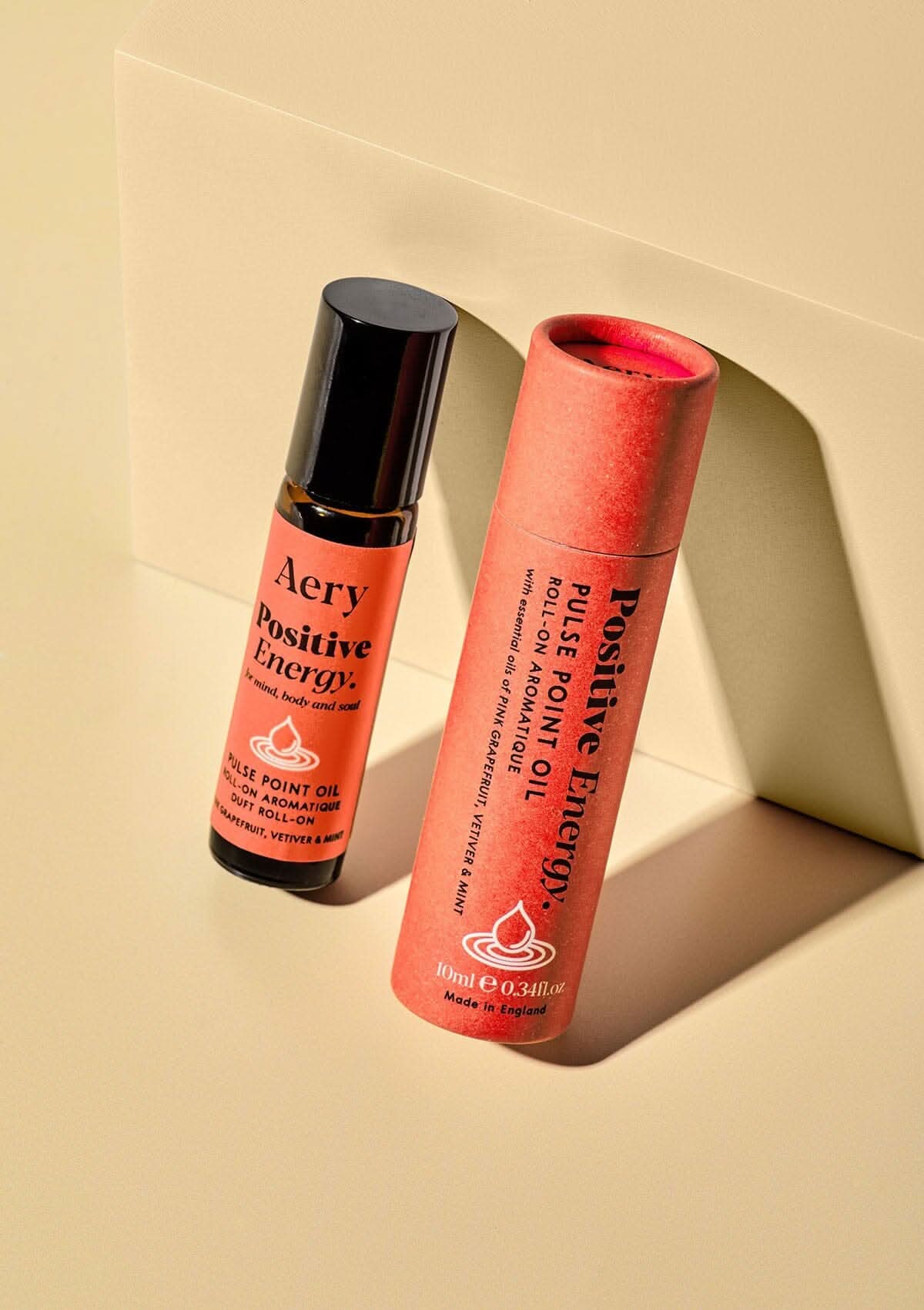 Red positive energy pulse point oil next to product packaging on yellow packaging
