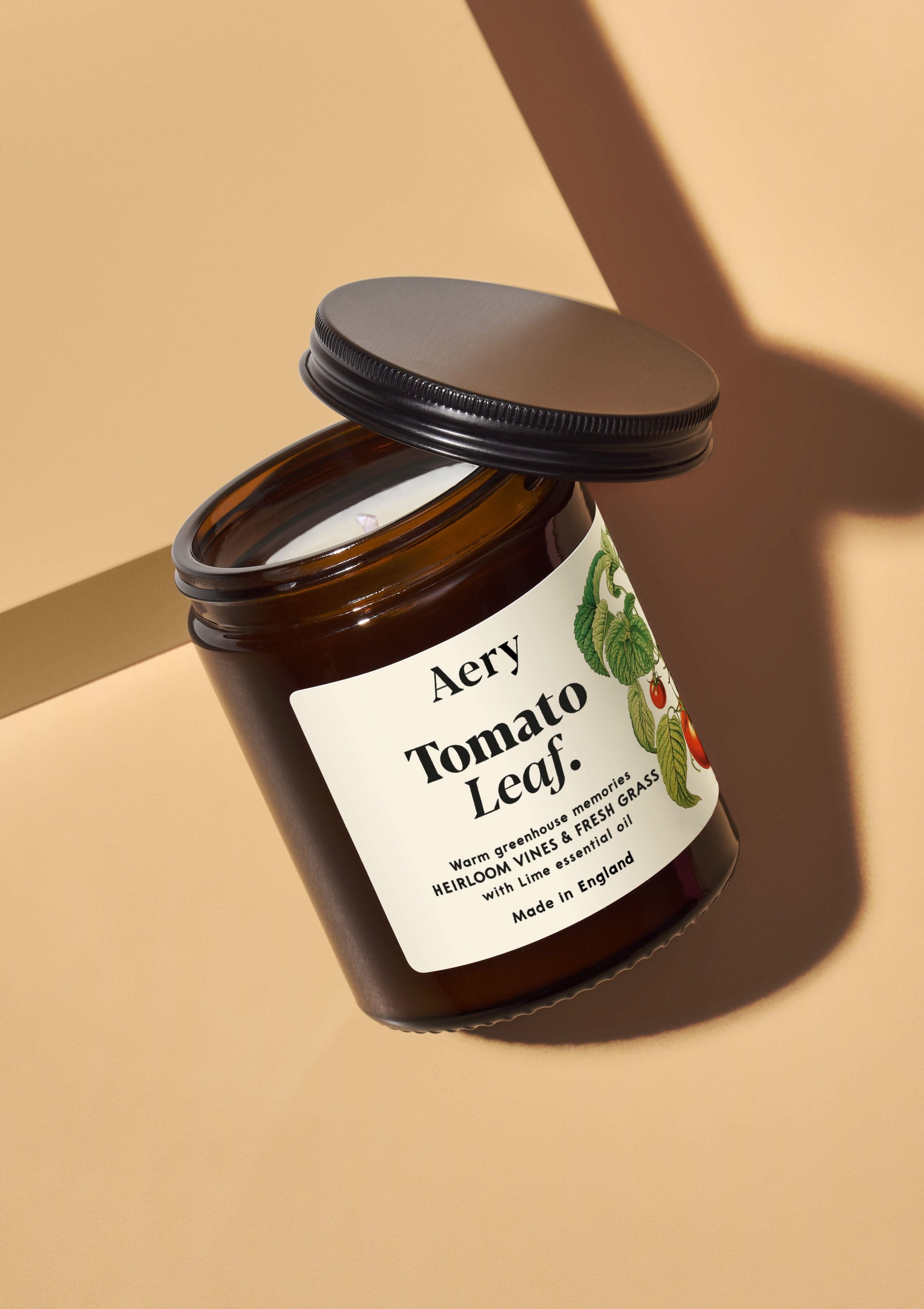 tomato leaf amber glass jar candle with decorative label on coloured bacground