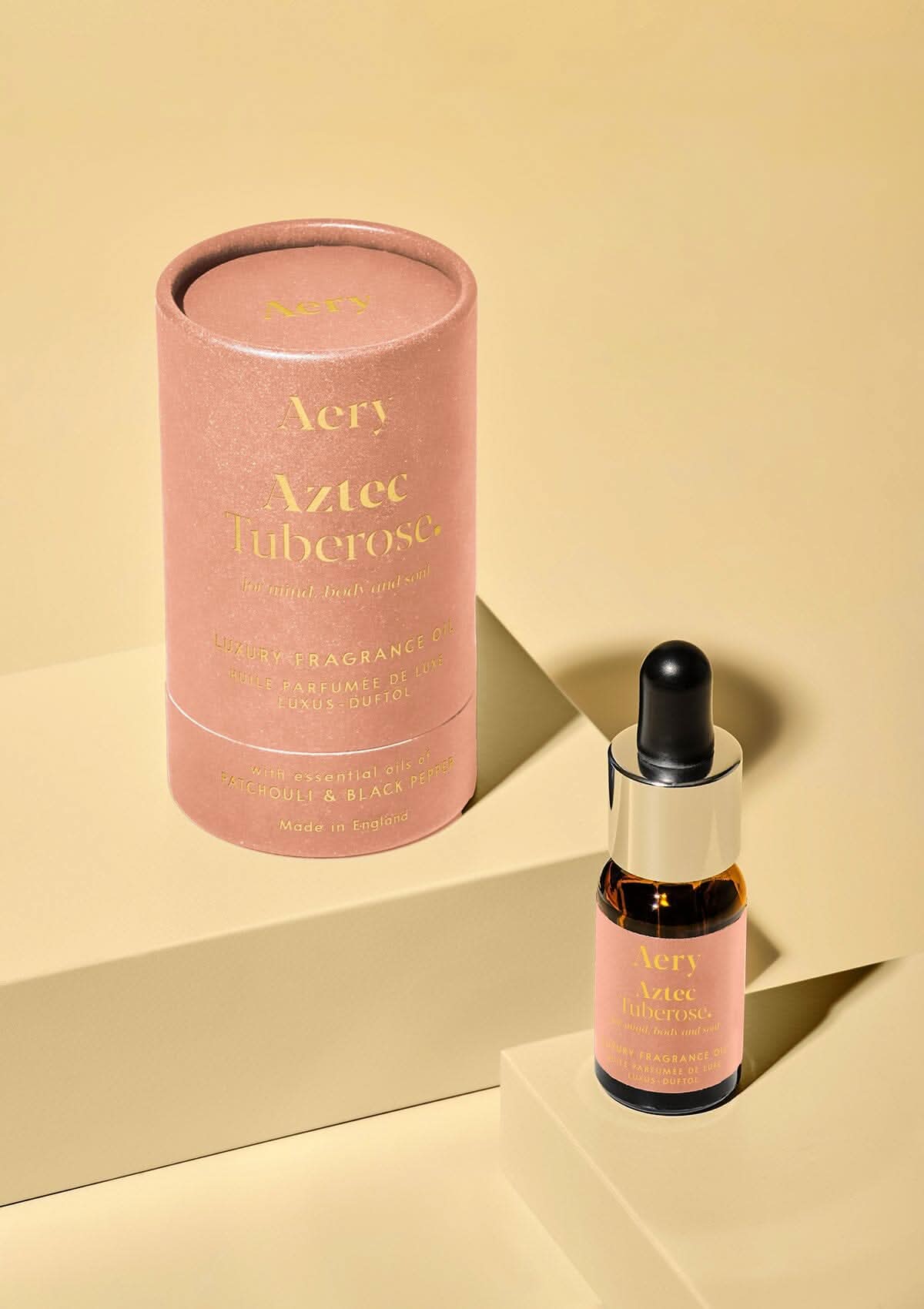 Pink Aztec Tuberose fragrance oil by aery displayed next to product packaging on yellow background