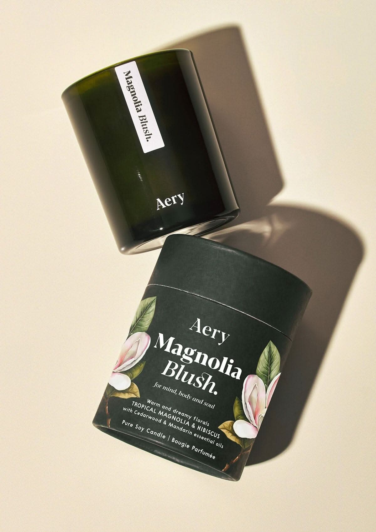 Magnolia Blush scented candle by Aery displayed with product packaging on cream bacground