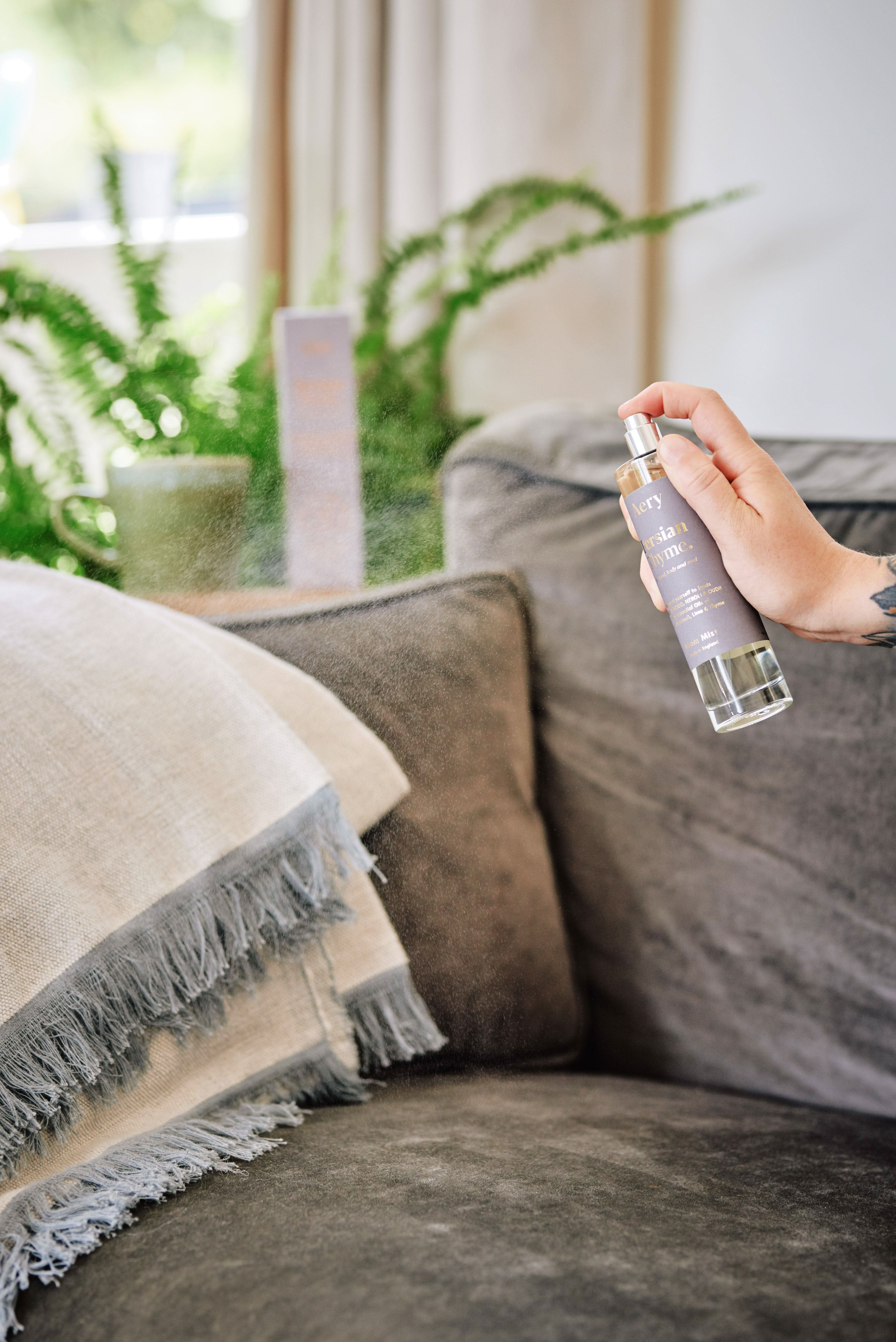 Grey Persian Thyme room mist by Aery displayed in hand spraying grey sofa